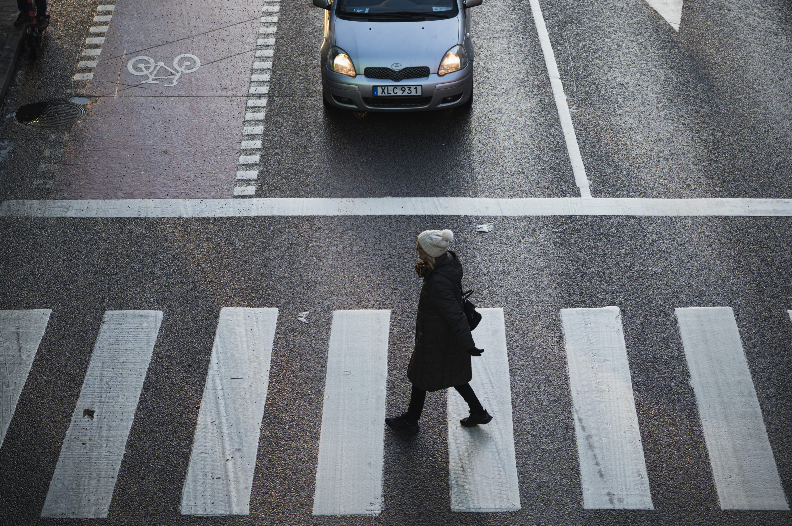 A woman crosses the road in front of a car